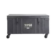Deco sejour, maison moderne de luxe, avec canapé en jaune moutarde, et bois noir, murs en gris anthracite, carrelage en dalles gris anthracite, grande malle en noir avec des fermoirs en métal jaune. Malle Indus A Roulettes En Metal Noire L 85 Cm Gibson Maisons Du Monde