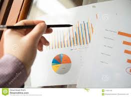 Male Hand Pointing At Charts Printed On A White Sheet Of