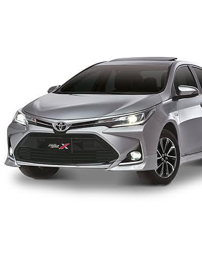 A sleek black car with a shiny, modern design is prominently displayed in a spacious and well-lit showroom. The showroom features large windows allowing natural light to pour in, highlighting the vehicle's features. Other cars are lined up in the background along the sides.