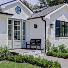 If painting the trim light or white doesn't brighten your home enough, paint your front door with a bold or bright color. White Painted Brick Exterior Light Blue Front Door Robins Egg Blue Door Black Gutters B Brick Exterior House White Brick Houses Painted Brick Exteriors