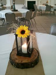 Put them in little vases (or just bottles) and place on every table along with candles, you can choose. Lantern With Candle And Sunflower On Top And A Raffia Bow Sunflower Wedding Centerpieces Rustic Sunflower Wedding Sunflower Wedding Decorations