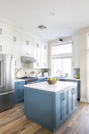 This Charming White And Blue Kitchen Boasts A Blue Island Accented With Oil Rubbed Bronze Pulls And A White Quar Blue Kitchens Kitchen Design Cheap Countertops
