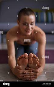 Close up female feet while stretching on mat. Stretching in Seated forward  bend exercise, paschimottanasana pose. Cheerful woman clothed in sportswear  Stock Photo - Alamy
