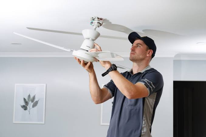 Specialist fitting a ceiling fan and light kit in DA8