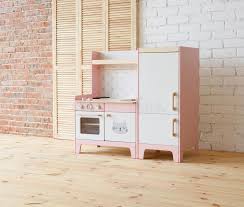 I prefer wooden play kitchen sets over plastic because they are nicer looking, more durable and hold their appearance longer than plastic kitchen sets. Play Furniture For Children Pink And White Wooden Toy Kitchen With Sink Oven And Fridge In Light Room Stock Photo Image Of Decorated Apartment 142342834