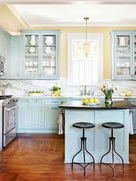 Blue backsplash tiles add a nice accent to the yellow cabinetry and white appliances in this kitchen with open shelving and natural hardwood flooring. Kitchen Cabinet Color Choices Kitchen Cabinet Colors Blue Kitchen Cabinets Home Kitchens