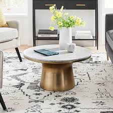 Twin leather sofas are matched by button tufted twin ottomans with hardwood frames, centered around large black wood square coffee table. West Elm Marble Topped Pedestal Coffee Table