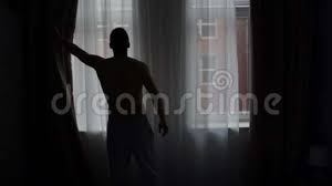 Man Silhouette Opening Curtain Looking Out Of Window Stock Footage Video Of Lookingaway Homeownerlifestyle 116178402 With no cords or tapes, the sheer facings allow you to view through the vanes to the outside while maintaining privacy. man silhouette opening curtain looking out of window