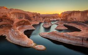 Glassy water merges with the stunning scenery. Lake Powell Visit Southern Utah