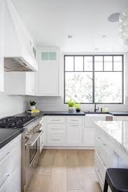 The granite countertops are complemented by the dark cabinets and tile framing the stove area, as well as the dark wooden chairs standing attention at this quaint kitchen expands itself with the use of white cabinets and matching fridge doors. White Kitchen Cabinets With White Granite Countertops Design Ideas