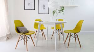 Yellow and black dining room features a black drum pendant illuminating a black french dining table with cabriole legs and a wood top lined with black and white french dining chairs atop a white and yellow floral rug placed in front of glass folding doors which open to the sunken backyard. Terni White Round Dining Table Traditional Dining Rooms Colored Dining Chairs White Round Dining Table