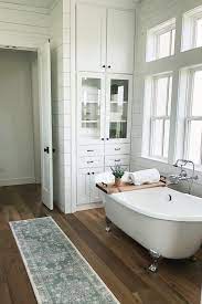 Wooden lines embrace a bathroom. Modern Farmhouse Bathroom White Walls Warm Wood Floors And A Clawfoot Bathtub Make T Modern Farmhouse Bathroom Farmhouse Master Bathroom Wood Floor Bathroom