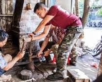 A tourist learning to forge a knife at a blacksmithing workshop.