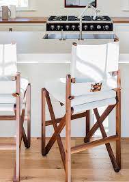 A line of nailhead trim around the base of the seat adds an industrial touch to this otherwise. White Kitchen Island With White Leather Director Counter Stools Cottage Kitchen