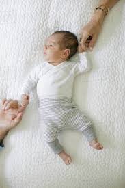 Baby Boy Lying On Bed, Mother And Father Holding Baby's Hands, Overhead  View - Stock Photo - Dissolve