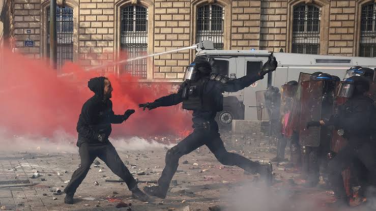 French riot police deploy tear gas and clash with demonstrators near barricades in central Paris as nighttime riots intensify across the capital., AI generated