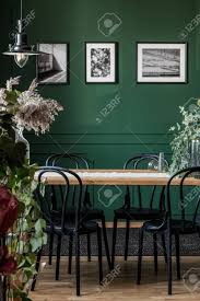 Two chairs are sold for the price of one, giving you more freedom to decorate your home the way you want it in an affordable way. Real Photo Of Black Chairs Standing At A Wooden Table In Elegant Dining Room Interior With Framed Photos On Green Wall Stock Photo Picture And Royalty Free Image Image 125785288