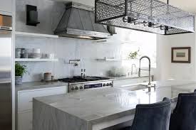 Industrial Style Kitchen With Iron Cage Pendant And Waterfall Island Transi Industrial Style Kitchen Kitchen Industrial Style Stainless Steel Kitchen Remodel