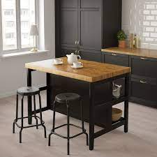 La table en bois reprend le matériau du plan de travail et réchauffe l'îlot de couleur noire. Vadholma Ilot Pour Cuisine Noir Chene 126x79x90 Cm Ikea
