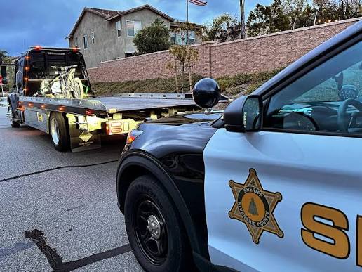 Sheriff vehicle and tow truck carrying an impounded electric dirt bike