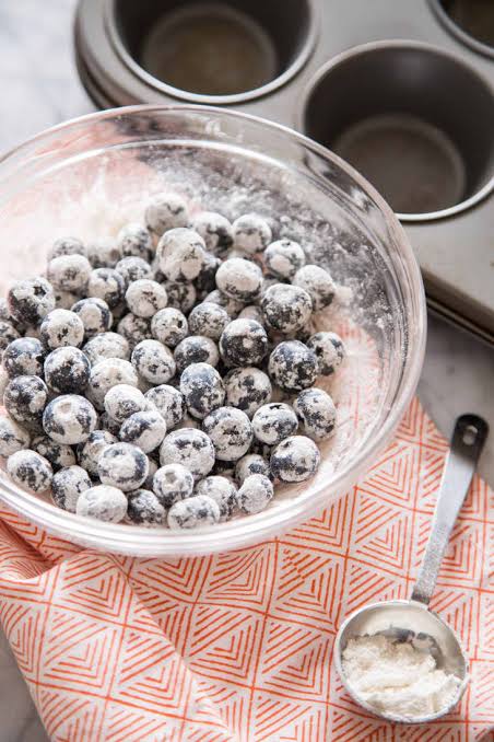 Tossing blueberries in flour keeps them evenly distributed throughout the muffin, AI generated