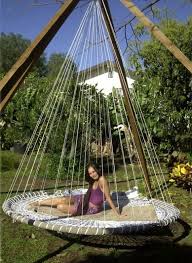 A comfy hanging bed on ropes hanging on a tree with colorful boho bedding feels and looks. Think Relaxation 42 Outdoor Hanging Beds Comfydwelling Com