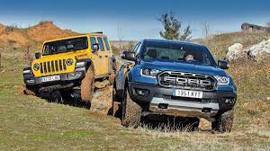Coches jeep raptor de dos modelos distintos de color azul y verde. Jeep Wrangler Rubicon Vs Ford Ranger Raptor Extremos Autofacil