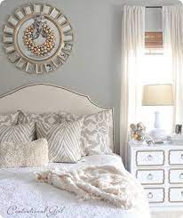 White and gold bedroom features gold art placed above a white headboard on king bed dressed in white bedding and a blue chevron lumbar pillow chic blue bedroom features a white oval sunburst mirror placed over a gray french desk accented with gold leaf trim paired with a turquoise blue x stool. In Love With Silver And Gold Home Bedroom Home Home Decor