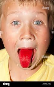 A seven year old boy shows his red tongue after drinking a strawberry slush  puppy drink Stock Photo