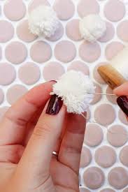 After you finish wrapping the yarn onto the pom pom maker, hold it closed and cut both sides following the guides. Diy Pom Pom Earrings