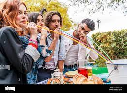 group of multi-cultural friends having fun at the garden party sucking beer  from colorful straws from a cooler Stock Photo - Alamy