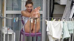 Eine Frau im Upskirt auf dem Balkon wird von einem Voyeur-Nachbarn gefilmt