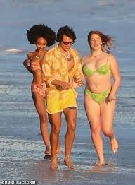 Harry Styles Is Chased Down The Beach By Dozens Of Models Harry Styles Style Orange Floral Shirt