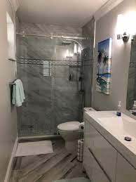 Although surrounded by contemporary decor, a round mirror covered with reclaimed twigs pulls the entire organic look together. Bathroom Designs Factory Direct Renovations Group