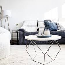In photos it's a very sophisticated looking table, made from a metal frame which forms a series of pentagons and triangles, and a tiled top which resembles marble from afar but looks more like tile or maybe blocks of ivory up close. Origami Coffee Table