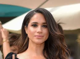 Young woman with black hair, fitness instructor in white swimwear doing stretching and pilates on yoga mat by the sea on a sunset. On Meghan Markle Race And Royalty Vogue