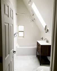 Attic bathroom features a sloped cieling dotted with rustic wood beams over an oval tub with marble deck placed under a window next to a white footed linen cabinet. 48 Awesome Attic Bathroom Design Ideas Small Attic Bathroom Attic Bathroom Attic Remodel