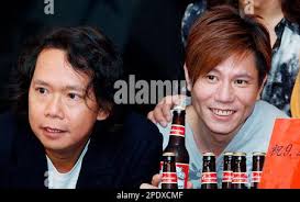Joey Tang, left, and Patrick Lui, key members of Hong Kong's veteran rock  band, Tai Chi Band, hold bottles of beer to celebrate the band's 20th  birthday in Hong Kong Monday, Aug.