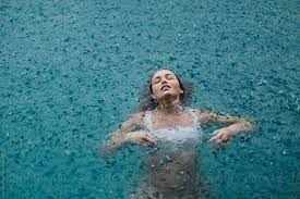 woman in a pool swimming in the rain stocksy united pool photography rain photography water photography