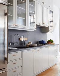 Here, gold handles connect white cabinets to complementary light green cabinetry beneath a white marble counter. Grey Kitchen Black Handles