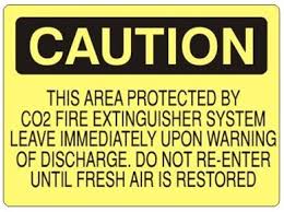 It recognizable as a yellow triangle with a solid black border and a black pictogram on it. Caution This Area Protected By Co2 Fire Extinguisher System Sign