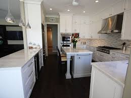 A pale mint kitchen with a white marble backsplash, countertops and an long open shelf. An Airy Model Kitchen Home Remodel Laguna Niguel