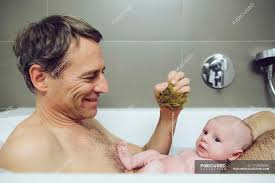 Until the umbilical cord falls off, it is best to give your baby sponge baths. Father And Baby Taking A Bath With A Natural Sponge Together Cute Stock Photo 173092050