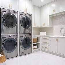 Two Sets Of Stacked Washers And Dryers Framed By Cabinets Laundry Room Design Laundry Room Remodel Farmhouse Laundry Room