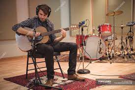 Maybe you would like to learn more about one of these? Man Sitting On Chair And Playing A Guitar In Music Studio Performance Rehearsing Stock Photo 225327520