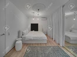 L'arredamento in una camera da letto matrimoniale moderna deve rispondere ad questo, bianco e imbottito, esprime uno charme che è tutt'uno con la raffinatezza dell'intera stanza, che gioca con il duo cromatico del bianco e del grigio. Immagini Stock Camera Da Letto Moderna Con Pareti Bianche E Un Parquet Con Un Tappeto Sul Pavimento C E Un Letto Con I Cuscini Bianchi E Coperte Comodini Lampade A Sospensione Di