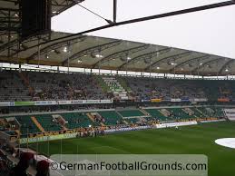 Showing a father and his child walking in front of the vfl stadium it clarifys how soccer is linked to familiy and tradition. Volkswagen Arena Vfl Wolfsburg German Football Grounds