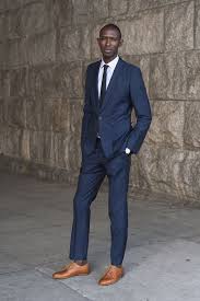 His pairing of medium brown shoes with a navy suit lends a beautiful contrast to the eye that in my opinion could never be done by pairing a solid black navy suits: Stop Wearing Tan Shoes With Dark Suits Put This On