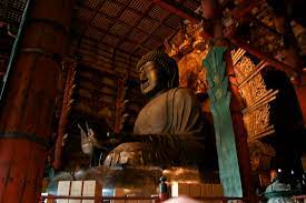 The image is a picture of a large statue of a Buddha. The statue is seated and is within a building.