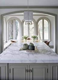 In this kitchen, the natural cream and beige hues work with the gray flecks in the countertop to pull together the suede grey cabinets, as well as the beautiful mosaic backsplash. Marble White Marble Kitchen White Marble Countertops White Marble Kitchen Countertops